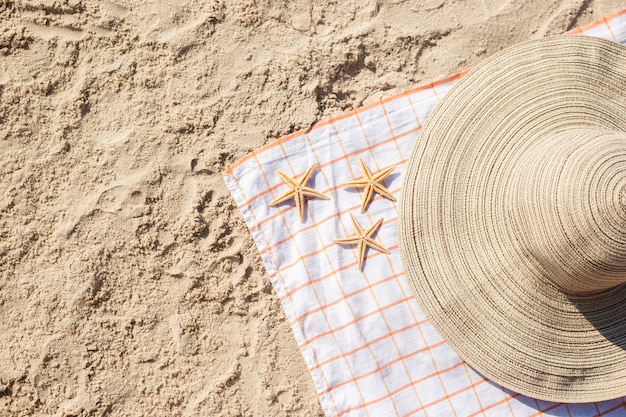 Estrella de mar dorada, sombrero en la playa de arena. Vista superior, endecha plana.