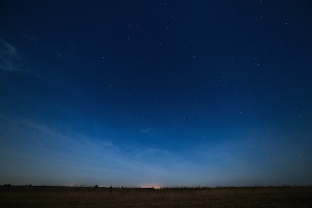 Foto estrellas en el cielo nocturno con luces de la ciudad en el horizonte. el paisaje está fotografiado por la luz de la luna.