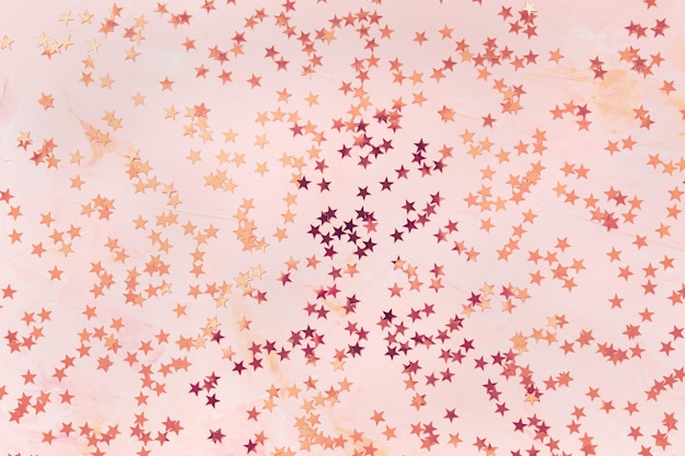 Estrellas de confeti de lámina de bronce sobre fondo rosa
