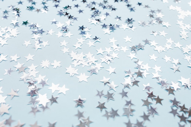 Estrellas de confeti de lámina de plata sobre fondo azul.