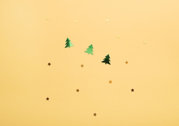 Estrellas doradas y arbolitos de Navidad sobre fondo amarillo