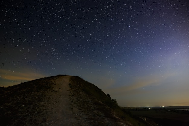 Estrellas del espacio ultraterrestre en el cielo nocturno sobre el valle del río. Paisaje en el crepúsculo de larga exposición.