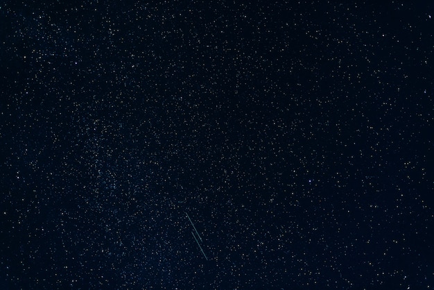Foto estrellas fugaces contra el azul estrellado del cielo nocturno con vía láctea