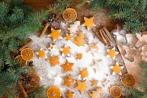 Estrellas de galletas de jengibre caseras, decoradas con azúcar en polvo y rodeadas de ramas de abeto y naranjas secas, canela.