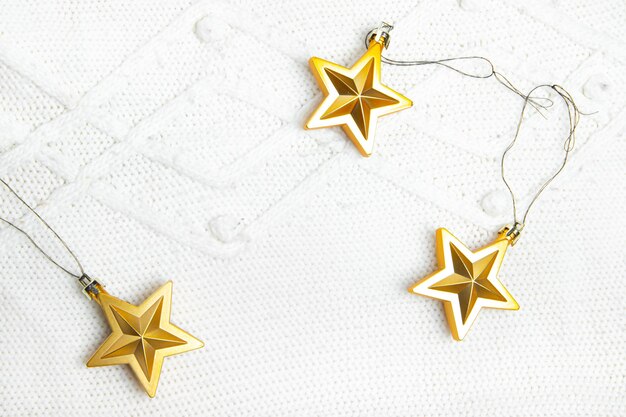 Las estrellas de juguetes navideños son doradas. Juguetes de Navidad dorados. Tejido de punto blanco. Fiestas de Navidad y año nuevo. Diseño navideño en la parte superior. Artículo sobre las vacaciones. Copia espacio