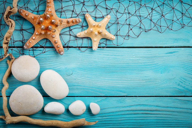 Estrellas de mar, guijarros y conchas sobre un fondo azul de madera. Hay un lugar para las etiquetas.