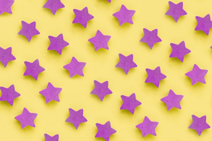 Foto estrellas rosadas en la superficie amarilla, lugar para el texto. galletas rosas copia espacio