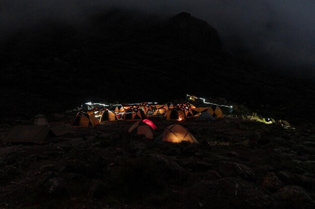 Estrellas sobre el monte Kilimajaro. Paisaje nocturno panorámico de la montaña africana más alta nevada, iluminada por la luna llena contra el cielo azul profundo con estrellas. Vista de la sabana