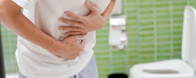 Estreñimiento y diarrea en el baño El hombre herido toca el vientre dolor de estómago doloroso