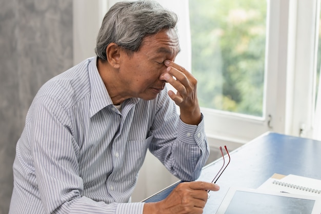 El estrés de los ancianos asiáticos cansado y la celebración de su nariz sufren fatiga del dolor sinusal del trabajo duro.