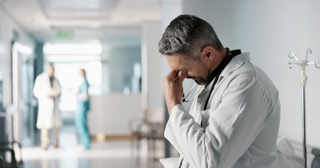 Foto estrés, dolor o fracaso con un médico maduro en un hospital que parece infeliz por la atención médica o médica, depresión, error o pérdida con un hombre triste, profesional de la medicina en una clínica profesional de atención médica.