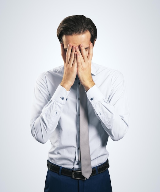 Estrés y encuentra el concepto de solución con el hombre de camisa blanca cerrando los ojos con la palma de la mano aislado en un fondo gris claro