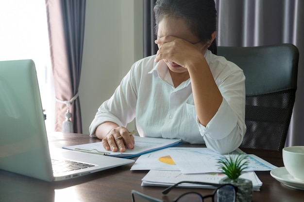 Estrés mujer de negocios persona de la depresión del trabajo duro en la oficina Empleada cansada y ansiosa con infeliz en el trabajo problemático joven empresaria sentada triste frente a la computadora portátil en el escritorio