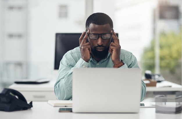 Estrés de pensamiento y hombre de negocios en la computadora portátil con dolor de cabeza, niebla cerebral y riesgo de salud mental para la tecnología de la información Fatiga por ansiedad o persona africana cansada en el problema de la computadora falla o se quema