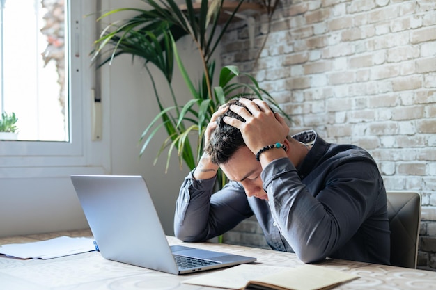 Estresado hombre cansado en el dolor que tiene un fuerte ataque de dolor de cabeza terrible después de la computadora