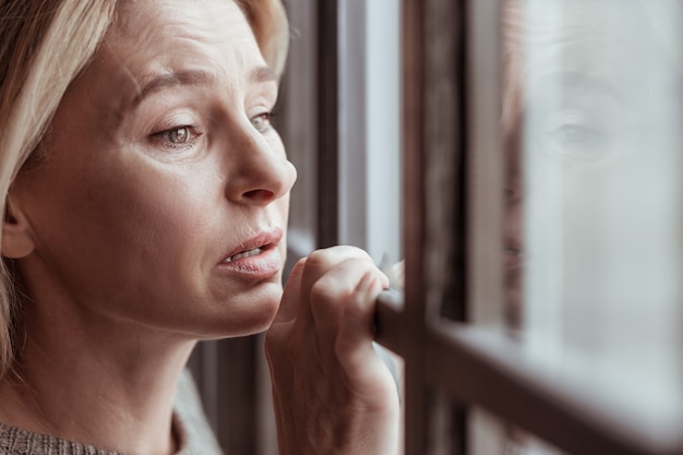 Estressado e triste. Mulher madura e atraente de cabelos loiros com rugas faciais, sentindo-se estressada e triste