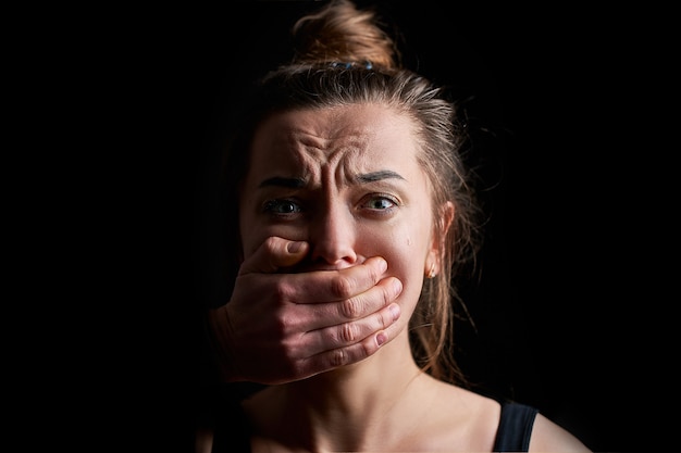 Foto estressado infeliz vítima de mulher chorando com medo com medo com a boca fechada em um preto escuro