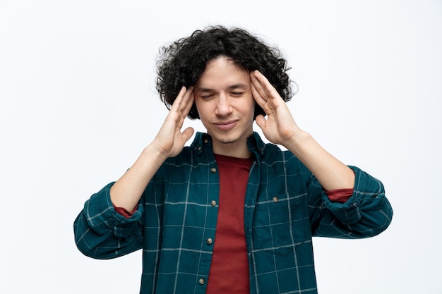 Foto estressado jovem bonito, mantendo as mãos na cabeça com os olhos fechados, isolados no fundo branco