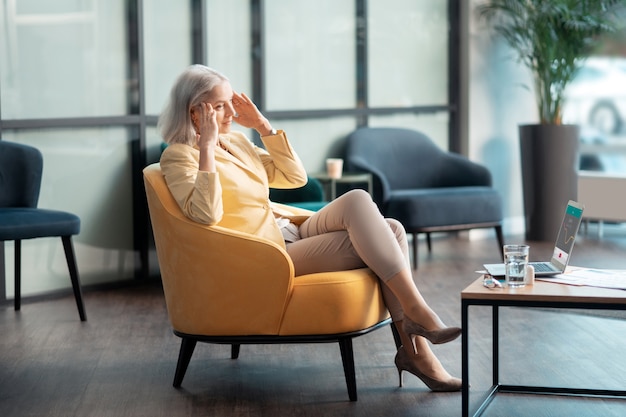 Estresse e dor de cabeça. vista lateral de uma mulher de negócios sênior com dor de cabeça temporal sentada no escritório