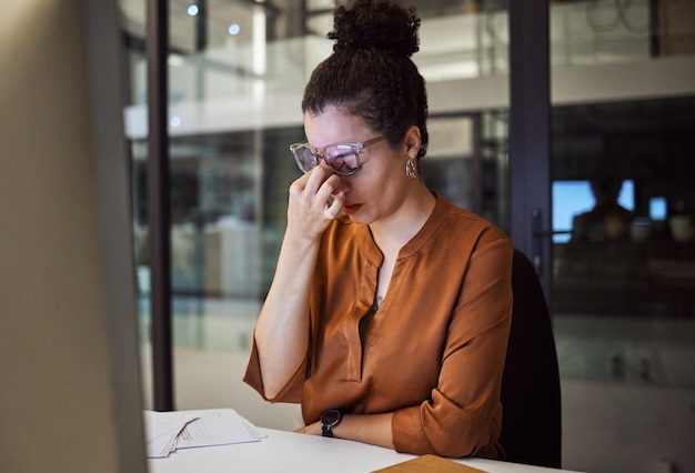 Foto estresse esgotado e mulher com dor de cabeça cansada de trabalhar horas extras em sua mesa de escritório devido a prazos de papelada fadiga saúde mental e administrador sobrecarregado frustrado com uma enxaqueca