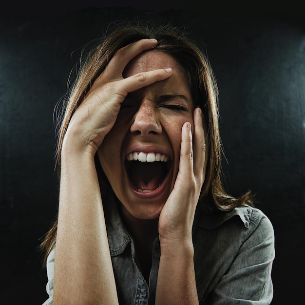 Foto estresse facial e horror com mulher gritando em estúdio em fundo preto para reação ao medo fobia ansiedade e saúde mental com jovem assustado no escuro para drama pesadelo ou terror