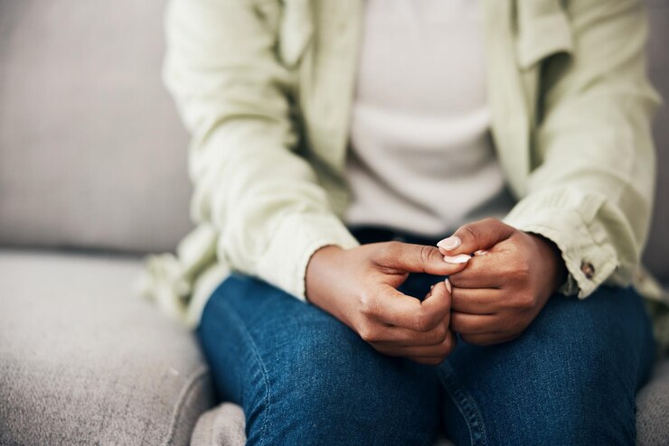 Foto estresse mãos e mulher em um sofá com ansiedade preocupação ou crise de saúde mental em sua casa depressão trauma e zoom em mulher com medo bipolar ou abuso perigo ou hábito nervoso de pegar unhas