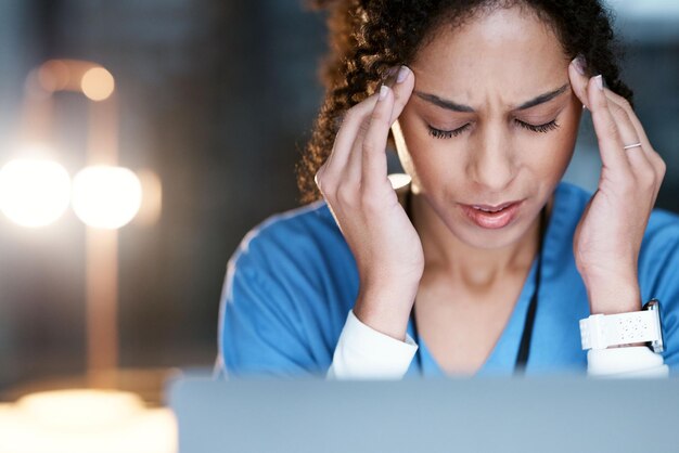 Foto estresse noturno e dor de cabeça com o médico no laptop para pensamento médico e revisão de prazo responsabilidade de burnout e saúde mental com mulher negra para medicina de saúde e pesquisa científica