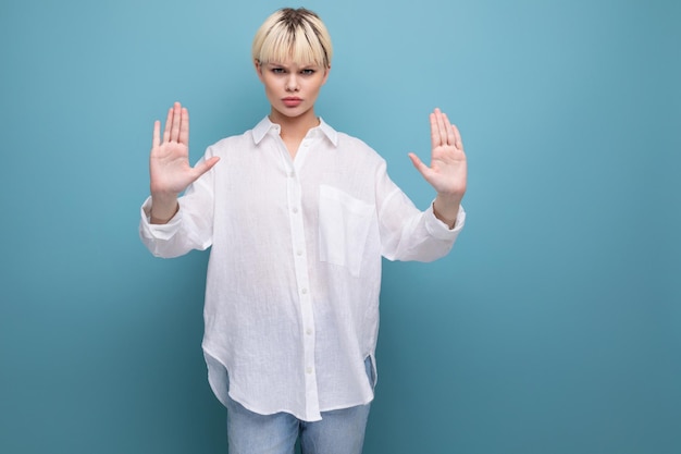 Estricta mujer de moda con un corte de pelo bob vestido con una camisa blanca muestra un gesto de parada