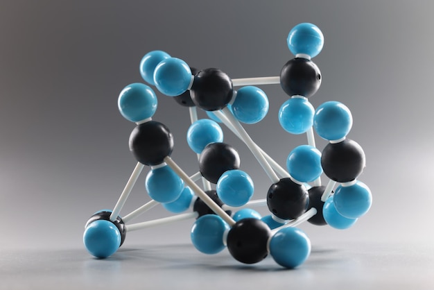 Estructura de modelo molecular en miniatura sobre fondo gris celdas azules y negras conectadas