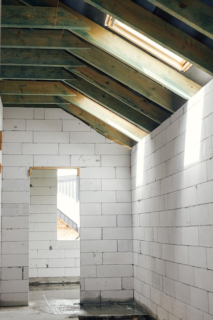 Estructura de techo de madera del ático inacabado con buhardilla y ventanas de barrera de vapor Vista sobre vigas de madera y vigas sobre bloques de hormigón aireado en buhardilla Nueva construcción moderna