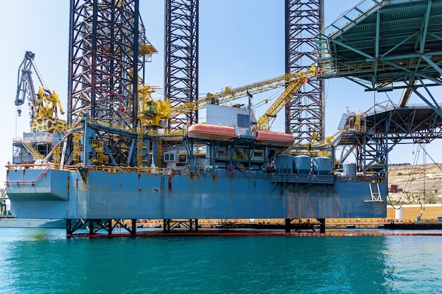 Las estructuras con equipos para la perforación de pozos de petróleo se encuentran en el mar cerca de una costa de Malta en el fondo del cielo azul.