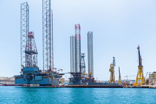 Estruturas com equipamentos para perfuração de poços de petróleo estão localizadas no mar perto de uma costa de Malta