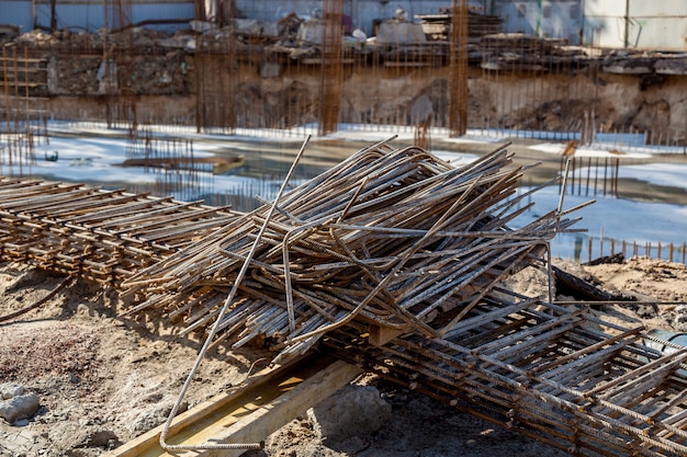 Estruturas metálicas para estruturas de concreto. local de construção, ferramentas, carrinho de mão, areia e tijolos na construção de uma nova casa, máquina misturadora de cimento e acessórios