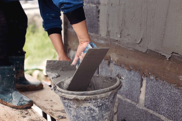 Estucadores de concreto para criar paredes de fundo de trabalhadores industriais com ferramentas de gesso.