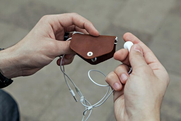 Estuche de cuero para auriculares en primer plano de manos de hombres