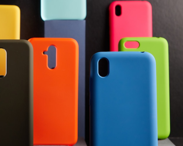 Los estuches coloridos para teléfonos inteligentes modernos se colocan en soportes sobre la mesa un objeto en foco fondo borroso