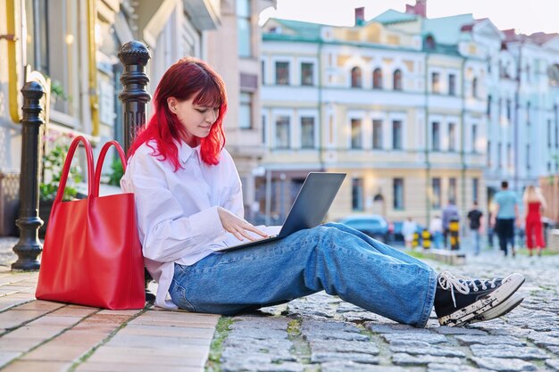 Estudante adolescente bonita e elegante usando laptop ao ar livre