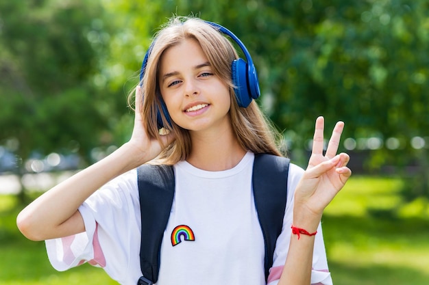 Estudante adolescente caucasiana ouvindo a música favorita do estéreo em fones de ouvido ao ar livre no parque da cidade