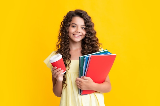 Estudante adolescente com livros e café sobre fundo amarelo Estudante sorridente