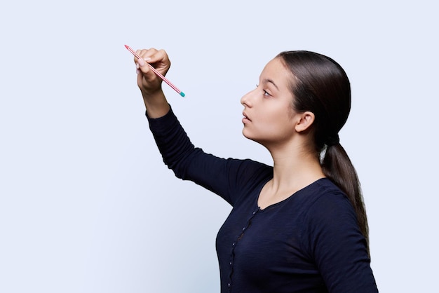 Foto estudante adolescente com um lápis desenha em uma tela abstrata