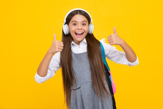 Estudante adolescente em fones de ouvido no fundo amarelo isolado do estúdio Conceito de escola de música Garota feliz enfrenta emoções positivas e sorridentes