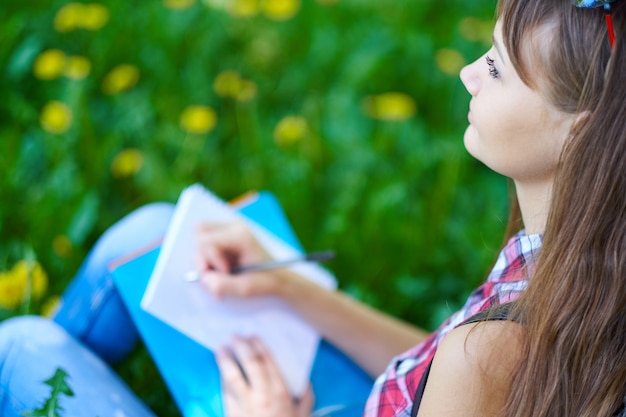 estudante adolescente escrevendo no caderno no parque. Preparação para exames na faculdade ou universidade