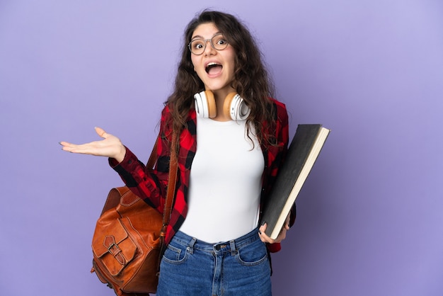 Estudante adolescente isolada em um fundo roxo com expressão facial chocada