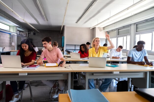 Estudante adolescente levantando o braço para fazer uma pergunta sobre a lição na sala de aula