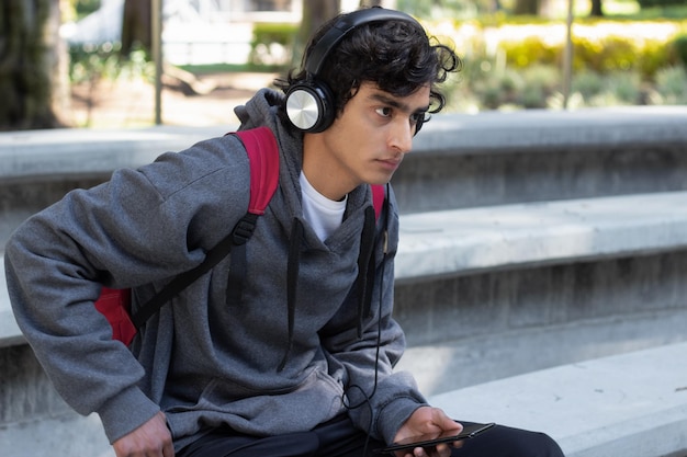 Estudante adolescente relaxando no parque ouvindo música com fones de ouvido