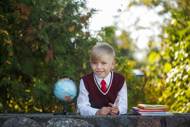 Estudante adorável com livros e globo no ar livre. Educação para crianças. Volta ao conceito de escola.