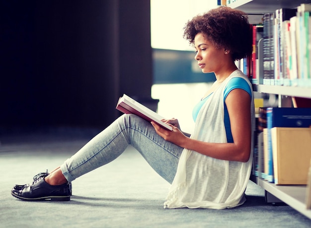 estudante africana lendo um livro na biblioteca