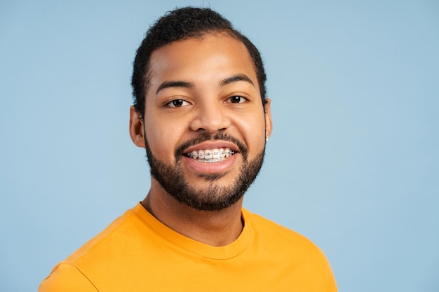 Estudante afro-americano de roupa casual olhando para a câmera e posando com um grande sorriso