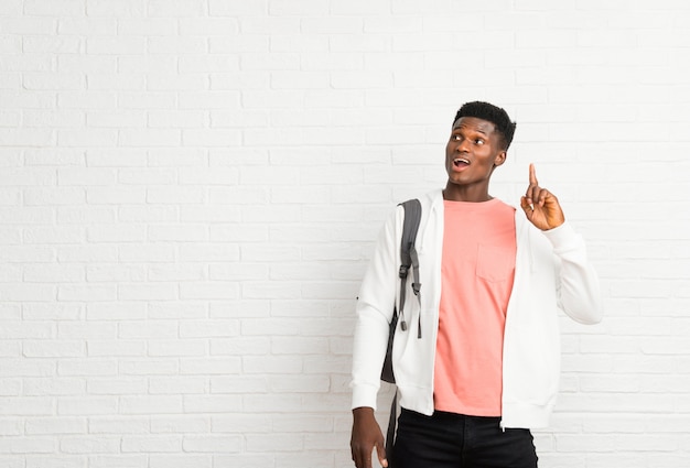 Estudante afro-americano novo do homem que pretende realizar a solução ao levantar um dedo acima