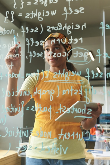 Foto estudante afro-americano usando um tablet para escrever códigos durante a aula de ti